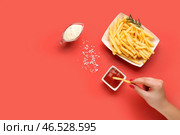 Женщина макает картофель фри в кетчуп на красном фоне. Стоковое фото, фотограф Pixel_shot / Фотобанк Лори