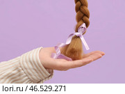 Женская рука с заплетёнными в косу рыжими волосами для пожертвования и ленточка для повышения осведомлённости на фиолетовом фоне. Стоковое фото, фотограф Pixel_shot / Фотобанк Лори
