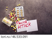 Бумажные карточки с текстом ПАНИЧЕСКАЯ АТАКА и разбросанные таблетки на сером фоне. Стоковое фото, фотограф Pixel_shot / Фотобанк Лори