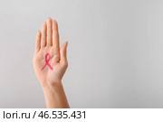Женщина с розовой лентой обращается на ее ладони на светлом фоне. Концепция осведомленности рака молочной железы. Стоковое фото, фотограф Pixel_shot / Фотобанк Лори
