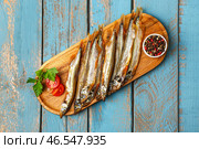 Доска с вкусной копченой мойвой на синем деревянном фоне. Стоковое фото, фотограф Pixel_shot / Фотобанк Лори