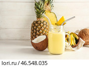 Банка со вкусным ананасовым смузи, соломкой и кокосовой стружкой на столе. Стоковое фото, фотограф Pixel_shot / Фотобанк Лори