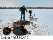 Ice hole sapropel extraction involves farmer using basket to collect goo, shoveling it to tank, and moving sludge via sled for organic agriculture. Стоковое фото, фотограф Владимир Григорьев / Фотобанк Лори