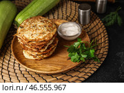 Тарелка вкусных кабачковых оладий с сметаной на черном фоне. Стоковое фото, фотограф Pixel_shot / Фотобанк Лори