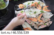 Assortment of fried shrimp, red mullet, sardines and megrim fillet seasoned with aromatic green herb oil sizzling in hot skillet on stove, creating hearty seafood dish. Стоковое видео, видеограф Яков Филимонов / Фотобанк Лори