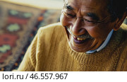 Cheerful elderly Asian man with gray hair, in a yellow sweater and a shining smile looks at the camera, 4k. Advertisement of a nursing home, an active lifestyle in retirement. Стоковое видео, видеограф ALLA YURTAYEVA / Фотобанк Лори