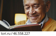 Cheerful elderly man with gray hair, in a yellow sweater and a shining smile looks at the camera, 4k. Advertisement of a nursing home, an active lifestyle in retirement, Handsome grandfather is thinking about something. Стоковое видео, видеограф ALLA YURTAYEVA / Фотобанк Лори