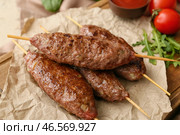 Деревянная доска с шампурами и вкусным люля-кебабом на столе, крупным планом. Стоковое фото, фотограф Pixel_shot / Фотобанк Лори