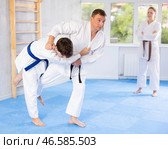 Judo or jiu-jitsu classes - two men practicing grabbing and throwing on sports mats under the guidance of trainer. Стоковое фото, фотограф Яков Филимонов / Фотобанк Лори