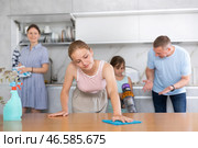 Teenage girl wiping table while cleaning house with family. Стоковое фото, фотограф Яков Филимонов / Фотобанк Лори