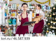 Female seller restocking using tablet while other is working in background. Стоковое фото, фотограф Яков Филимонов / Фотобанк Лори