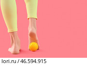 Спортивная молодая женщина массирует свою стопу мячом на красном фоне, вид сзади. Стоковое фото, фотограф Pixel_shot / Фотобанк Лори
