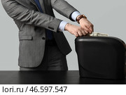 Молодой человек в костюме вытягивает долларовую банкноту из шредера на сером фоне, крупный план. Стоковое фото, фотограф Pixel_shot / Фотобанк Лори