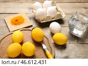 Самодельные крашеные пасхальные яйца, порошок куркумы и миска с водой на деревянном столе. Стоковое фото, фотограф Pixel_shot / Фотобанк Лори