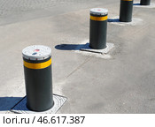 Дорожный блокиратор в виде выдвижных металлических столбов. The barrier is automatic in a parking lot in a modern city. Стоковое фото, фотограф Татьяна Д / Фотобанк Лори
