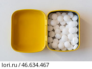Открытая желтая жестяная коробочка с белыми мятными леденцами на белом фоне. Стоковое фото, фотограф Anton Leonchikov / Фотобанк Лори