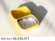 Открытая желтая жестяная коробочка с белыми мятными леденцами на белом фоне. Стоковое фото, фотограф Anton Leonchikov / Фотобанк Лори
