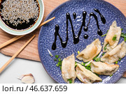 Тарелка с вкусной японской гёдза и соусом на белом фоне. Стоковое фото, фотограф Pixel_shot / Фотобанк Лори