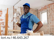 Cheerful plasterer standing with trowel in room under renovation. Стоковое фото, фотограф Яков Филимонов / Фотобанк Лори