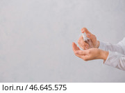 Женщина применяет дезинфицирующее средство на руках на сером фоне. Стоковое фото, фотограф Pixel_shot / Фотобанк Лори