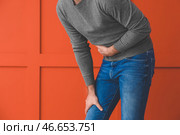 Молодой человек страдает от боли в животе на цветном фоне. Стоковое фото, фотограф Pixel_shot / Фотобанк Лори