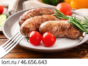 Тарелка с вкусными жареными колбасками на столе. Стоковое фото, фотограф Pixel_shot / Фотобанк Лори
