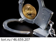 Физическая монета криптовалюты биткойн и наручники. Стоковое фото, фотограф Сергей Елагин/Бизнес Online / ТАСС / Фотобанк Лори