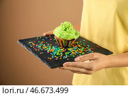 Женщина держит грифельную тарелку с вкусным кексом и брызгает на цветном фоне, близком расстоянии. Стоковое фото, фотограф Pixel_shot / Фотобанк Лори