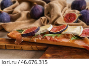 Вкусный бутерброд с спелый инжир, прошутто и сыр бри на деревянной доске, крупным планом. Стоковое фото, фотограф Pixel_shot / Фотобанк Лори