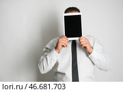 Бизнесмен скрывается лицо за планшетным компьютером на светлом фоне. Стоковое фото, фотограф Pixel_shot / Фотобанк Лори