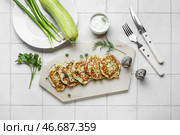 Доска с вкусными кабачковыми оладьями с сметаной на белом плиточном фоне. Стоковое фото, фотограф Pixel_shot / Фотобанк Лори
