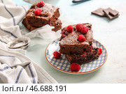 Бумажка для выпечки и тарелка с кусочками малиново-шоколадного брауни на светло-голубом столе. Стоковое фото, фотограф Pixel_shot / Фотобанк Лори