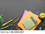 Калькулятор с свежим яблоком и различными канцелярскими принадлежностями на черной меловой доске. Стоковое фото, фотограф Pixel_shot / Фотобанк Лори