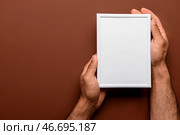 Мужчина, держащий пустую фоторамку на коричневом фоне. Стоковое фото, фотограф Pixel_shot / Фотобанк Лори