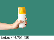 Женская рука с бутылочкой крема для солнцезащиты на зеленом фоне. Стоковое фото, фотограф Pixel_shot / Фотобанк Лори