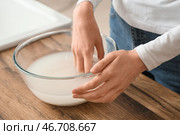 Женщина промывает рис в стеклянной миске рядом с деревянным столом, крупный план. Стоковое фото, фотограф Pixel_shot / Фотобанк Лори
