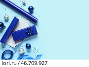 Подарочные рождественские коробки с упаковочными материалами и различными украшениями на синем фоне. Стоковое фото, фотограф Pixel_shot / Фотобанк Лори