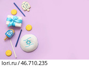 Композиция для празднования Хануки с кипой, подарочной коробкой и дрейдлами на сиреневом фоне. Стоковое фото, фотограф Pixel_shot / Фотобанк Лори