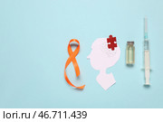 Изображение человеческой головы из бумаги с пазлом, ампулой, шприцем и оранжевой лентой на синем фоне. Месяц осведомленности о рассеянном склерозе. Стоковое фото, фотограф Pixel_shot / Фотобанк Лори