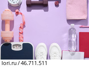 Рамка из весов с измерительной лентой, кроссовками и гантелями на сиреневом фоне. Концепция похудения. Стоковое фото, фотограф Pixel_shot / Фотобанк Лори