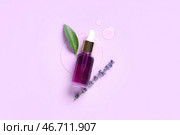 Флакон с лавандовым эфирным маслом, разлитое масло, зеленый лист и цветы на сиреневом фоне. Стоковое фото, фотограф Pixel_shot / Фотобанк Лори