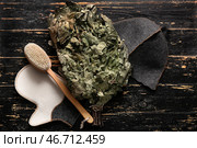 Дубовый веник, массажная щетка, войлочная перчатка и шапка для сауны на темном деревянном фоне. Стоковое фото, фотограф Pixel_shot / Фотобанк Лори