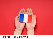 Женские руки с французским флагом на красном фоне. Празднование Дня взятия Бастилии. Стоковое фото, фотограф Pixel_shot / Фотобанк Лори