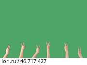 Женские руки, показывающие жест мира на зеленом фоне. Стоковое фото, фотограф Pixel_shot / Фотобанк Лори