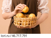 Женщина держит плетеную корзину с сырыми картофелинами на коричневом фоне. Стоковое фото, фотограф Pixel_shot / Фотобанк Лори