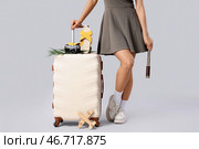 Молодая афроамериканка с чемоданом и аксессуарами на сером фоне. Стоковое фото, фотограф Pixel_shot / Фотобанк Лори