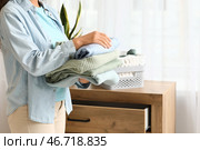 Красивая молодая афроамериканка с стопкой чистой одежды в спальне, крупным планом. Стоковое фото, фотограф Pixel_shot / Фотобанк Лори