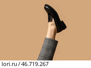 Нога молодой женщины в брюках и черных лакированных туфлях на бежевом фоне. Стоковое фото, фотограф Pixel_shot / Фотобанк Лори