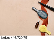 Плойка с щетками для волос, бутылка косметического продукта и прядь рыжих волос на бежевом фоне. Стоковое фото, фотограф Pixel_shot / Фотобанк Лори