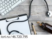 Компьютерная клавиатура с докторским стетоскопом, таблетками и блокнотом на деревянном фоне. Стоковое фото, фотограф Pixel_shot / Фотобанк Лори